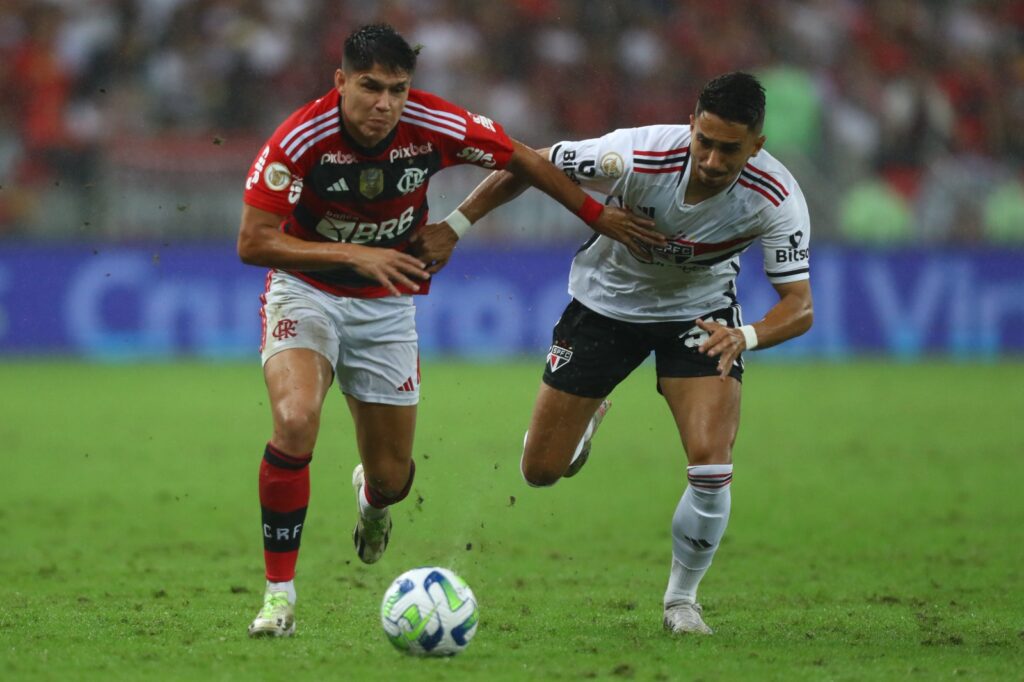 Luiz Araújo, do Flamengo, corre com a bola enquanto é perseguido por marcador do São Paulo;