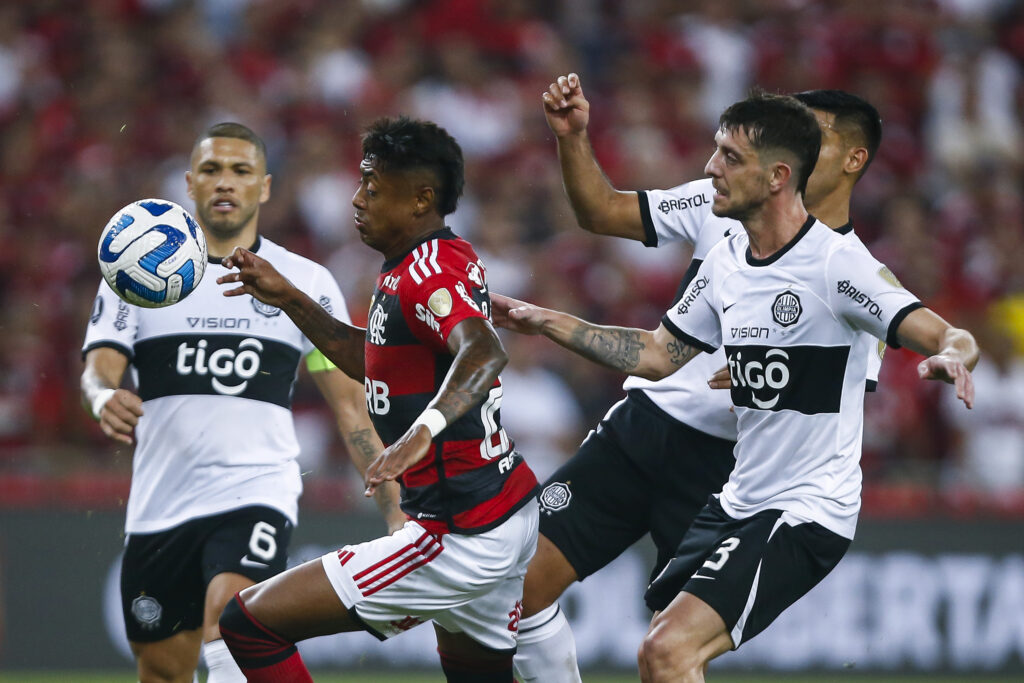 Bruno Henrique, do Flamengo, disputa a bola com jogadores do Olimpia