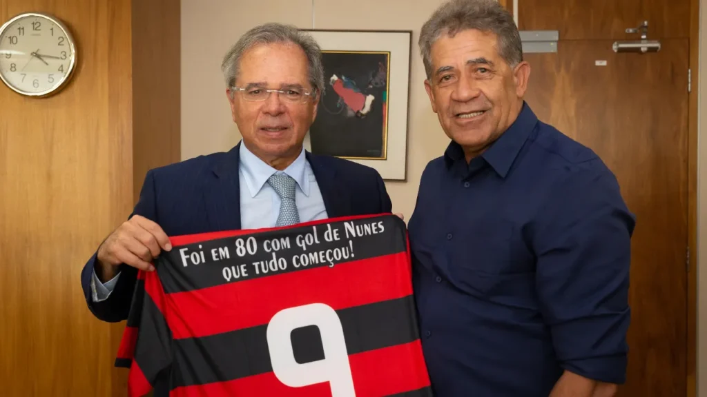 Paulo Guedes ao lado de Nunes com uma camisa do Flamengo com o número 9 e os dizeres "Foi em 80 com o gol de Nunes que tudo começou!"