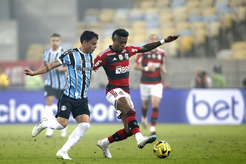 Bruno Henrique, do Flamengo, disputa bola com jogador do Grêmio; atacante rubro-negro está confirmado para a partida