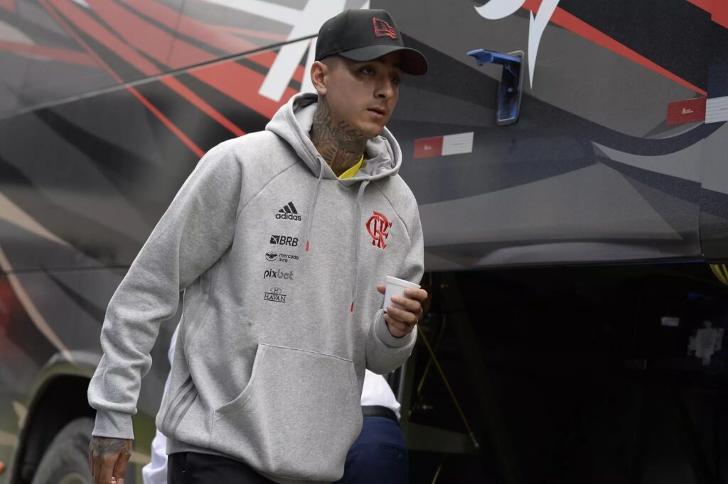 Erick Pulgar com boné e casaco do Flamengo prestes a subir no ônibus do clube; volante retorna após Chile ser eliminado da Copa América