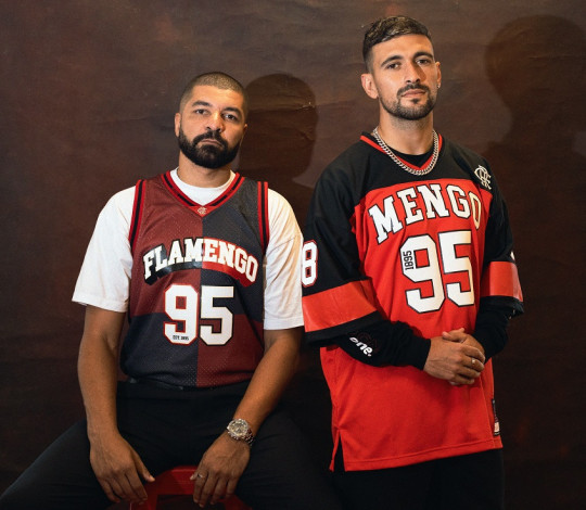 Olivinha e Arrascaeta, ídolos do Flamengo no basquete e no futebol, respectivamente, posam para foto com novas camisas incluídas na parceria do clube com a Mitchell & Ness, marca norte-americana de produtos esportivos