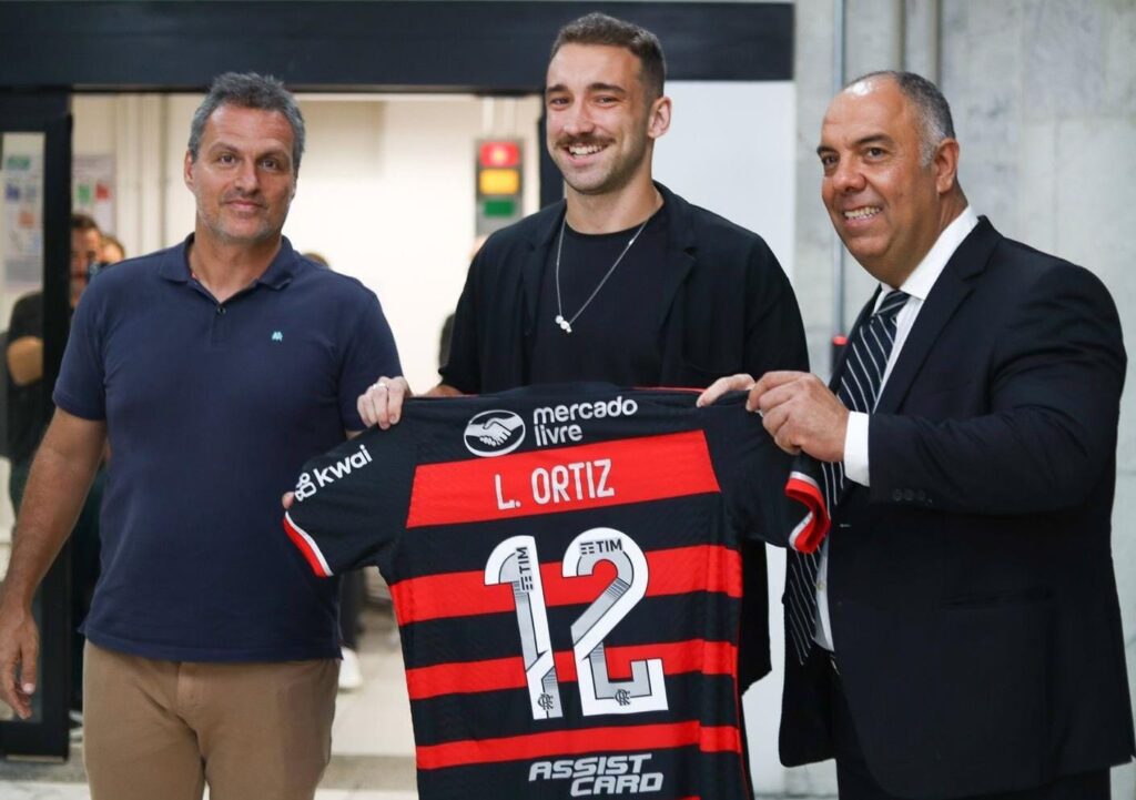 Léo Ortiz sorri com Braz e Spindel no aeroporto