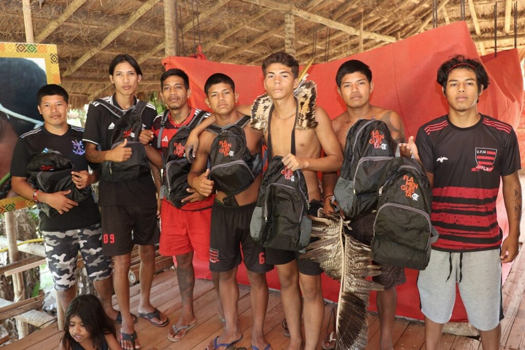 Indígenas da Aldeia Mata Verde Bonita com mochilas do Flamengo após clube levar projeto de leitura;