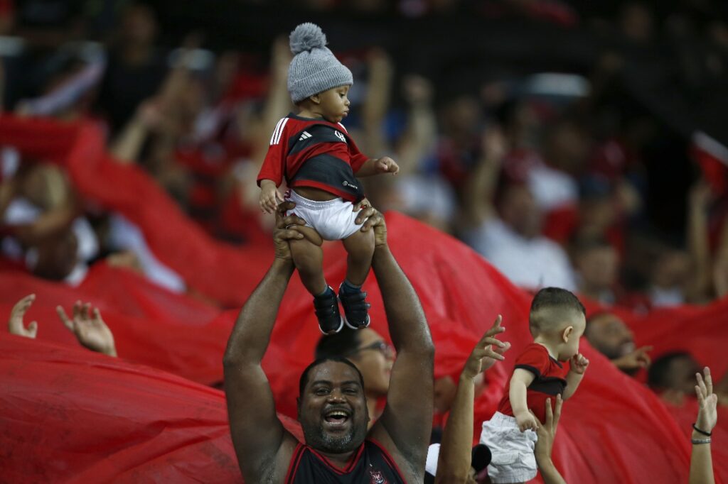 Torcedor levanta pequeno rubro-negro para o alto em comemoração a um gol do Flamengo