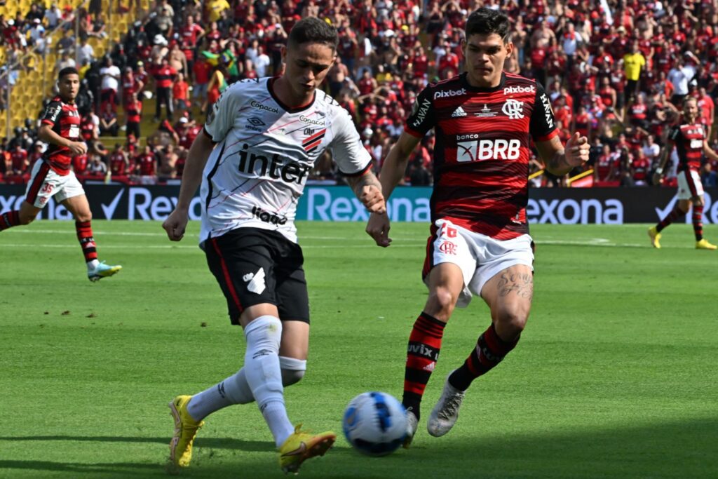 Khellven, ainda no Athletico-PR, passa a bola enquanto percebe aproximação de Ayrton Lucas, do Flamengo, na final da Libertadores de 2022