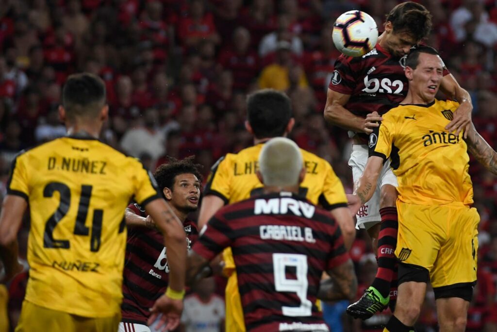 Gabigol observa Rodrigo Caio dividido bola aérea em Flamengo x Peñarol