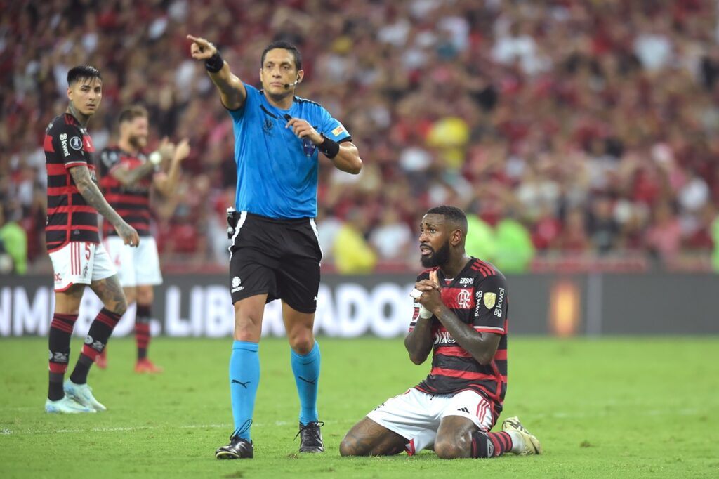 Gerson de joelhos se lamentando enquanto árbitro Jesus Valenzuela sinaliza marcação em Flamengo x Peñarol pela Libertadores 2024