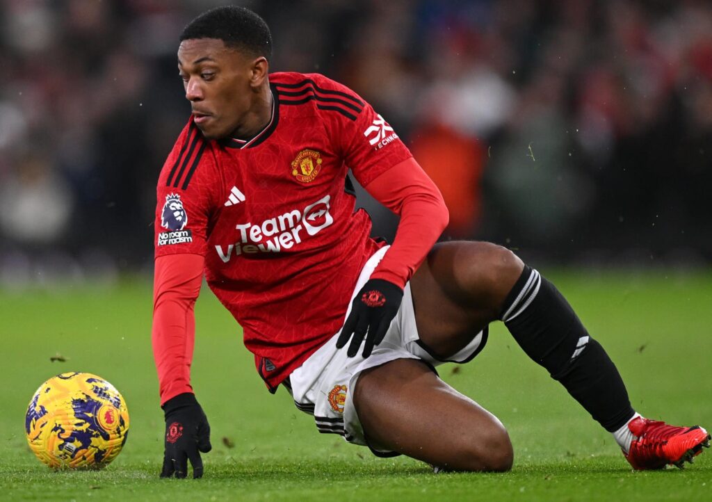 Martial no chão olhando para o lado para proteger bola