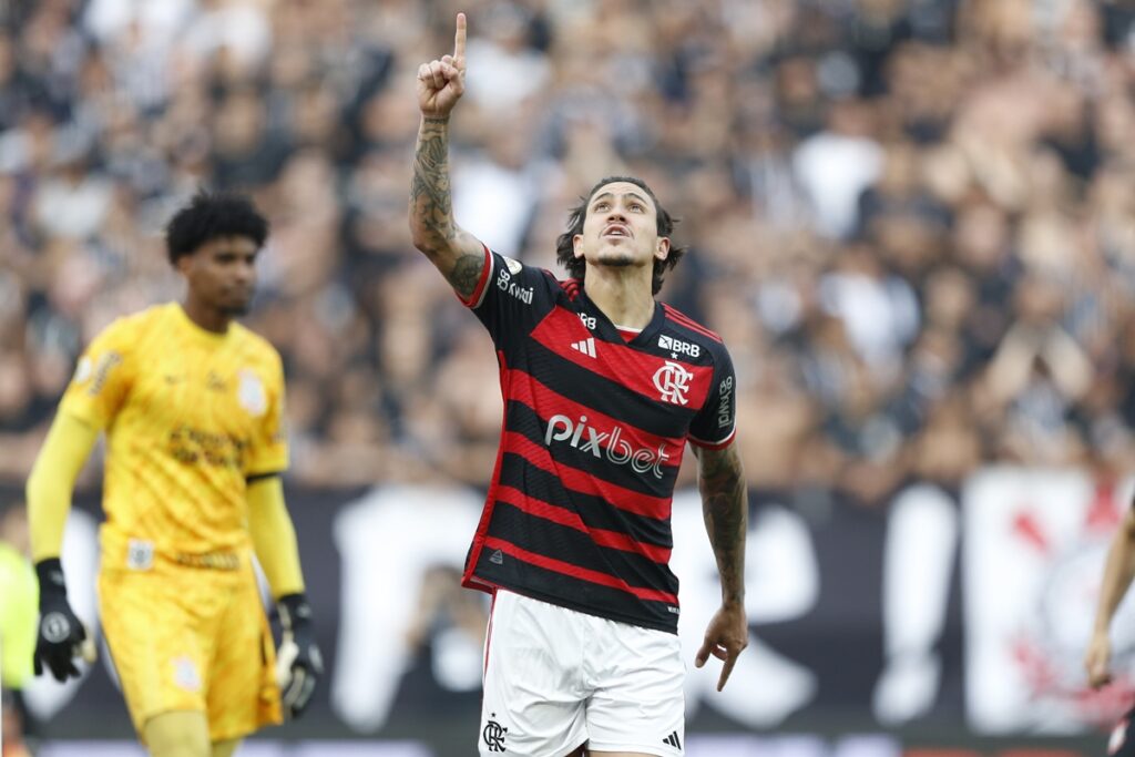 Pedro comemora gol do Flamengo apontando para o céu; ao fundo Hugo Souza, do Corinthians, se lamenta por ser vazado