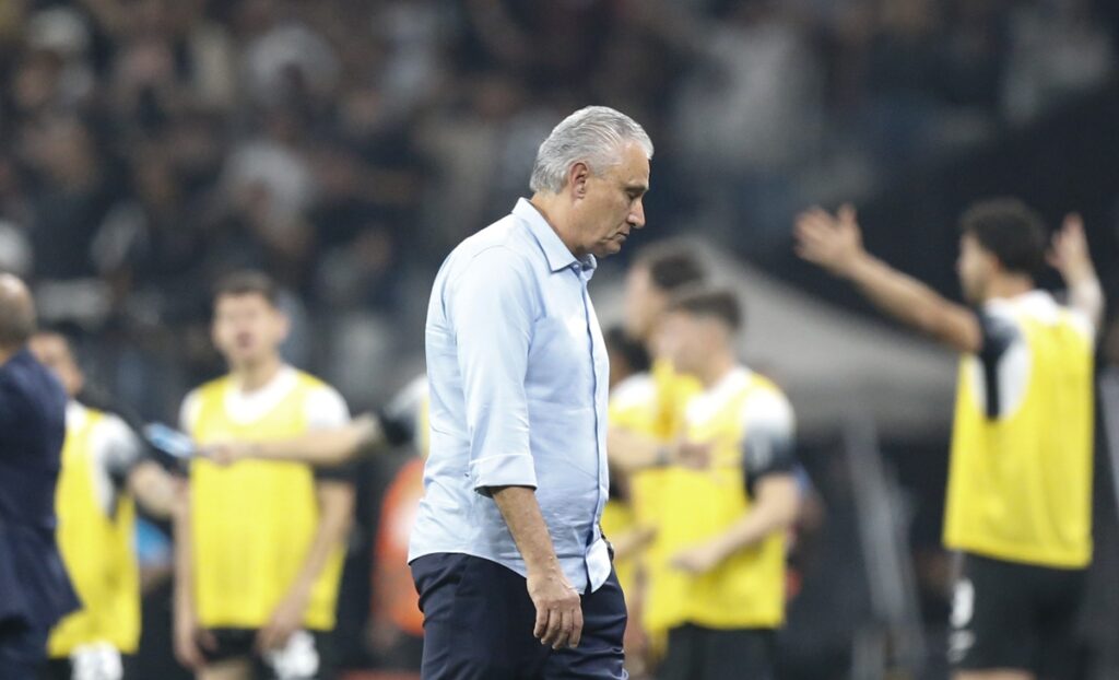 Tite cabisbaixo após derrota do Flamengo para o Corinthians; ao fundo jogadores e comissão do time paulista celebra