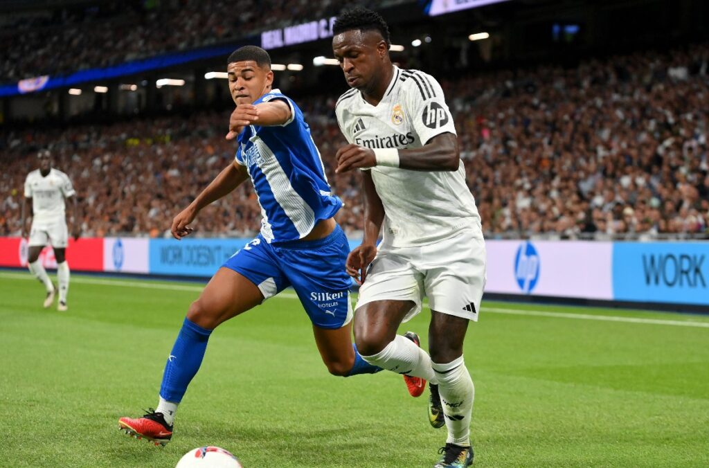 MADRI, ESPANHA - 24 DE SETEMBRO: Vinicius Junior, do Real Madrid, corre com a bola sob pressão de Santiago Mourino, do Alavés, durante a partida da LaLiga entre o Real Madrid CF e o Deportivo Alavés no Estádio Santiago Bernabeu em 24 de setembro de 2024 em Madri, Espanha.